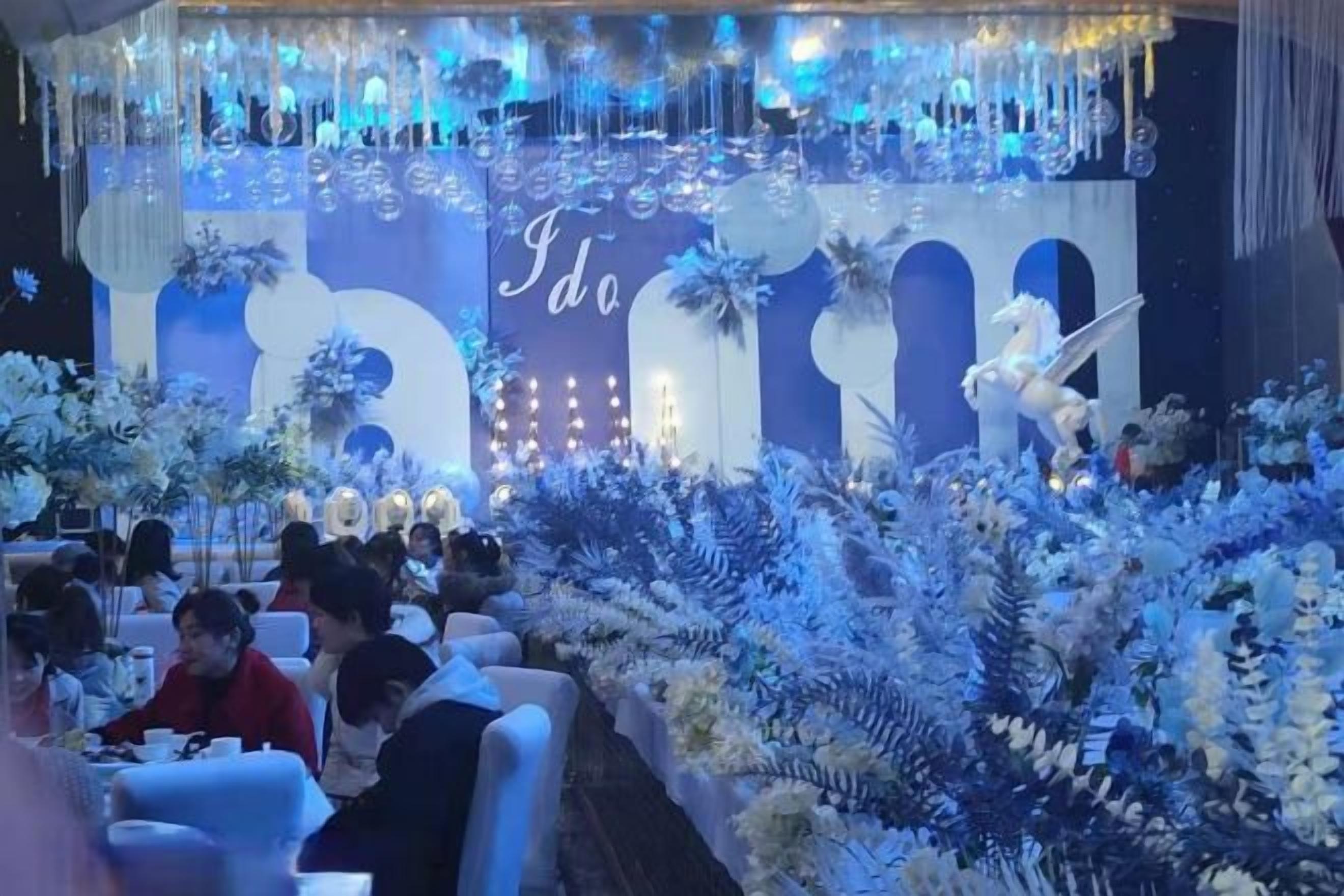 A formal event with a stage, floral decorations, and seated guests.