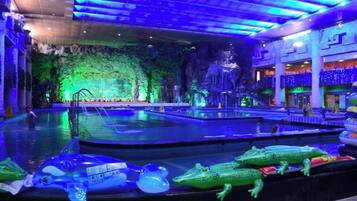 An indoor pool area with multiple water features, including a waterfall and a pool with a rocky backdrop.
