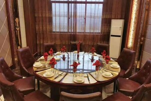 Una mesa de comedor redonda con sillas, cubierta con platos blancos, servilletas rojas y copas de cristal.