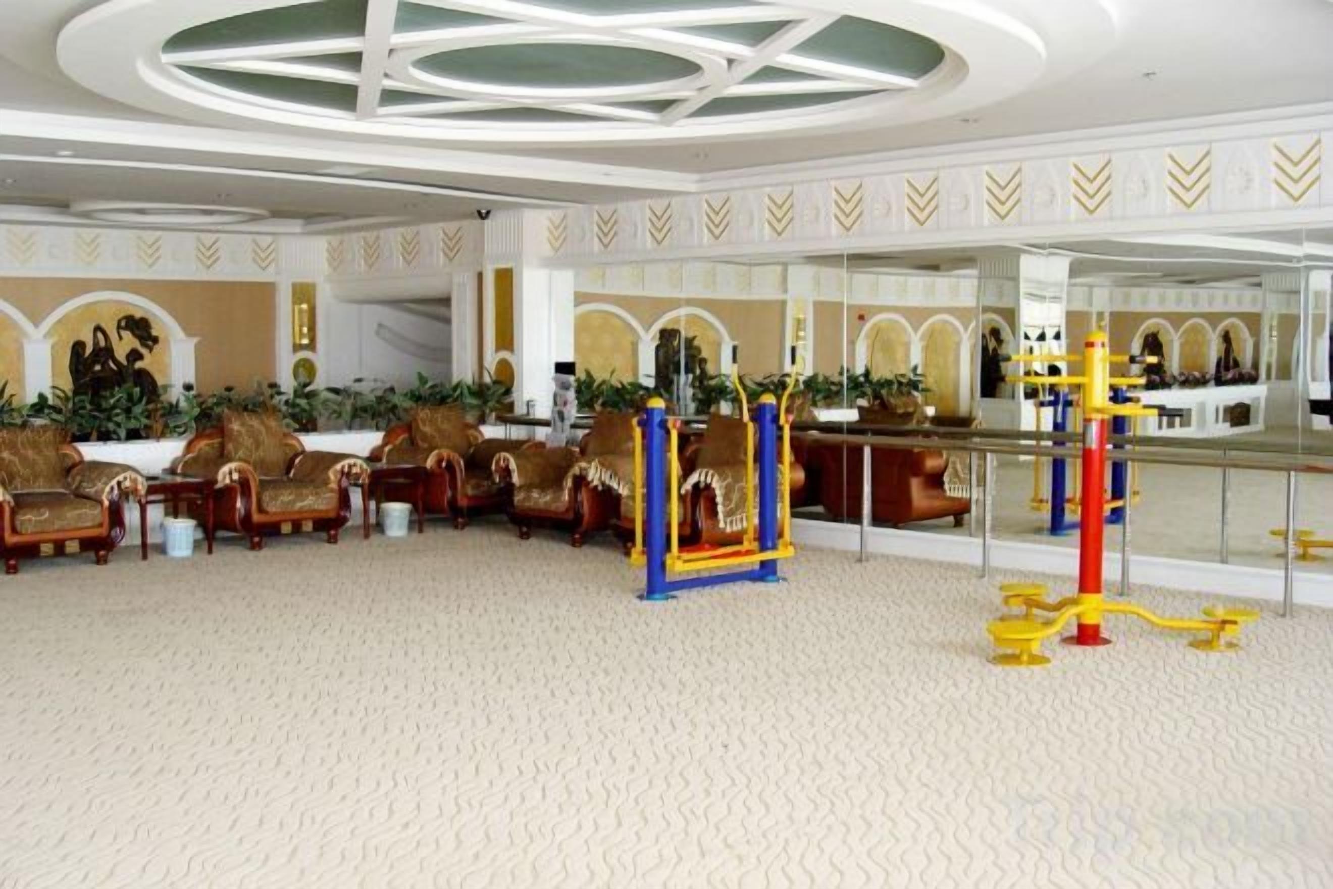 Un hall de hotel con mostrador de recepción, zona de estar con sillones y un área de juegos para niños.