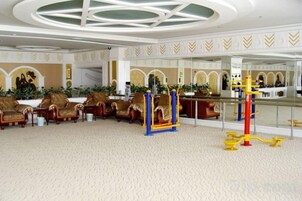 Un hall de hotel con mostrador de recepción, zona de estar con sillones y un área de juegos para niños.