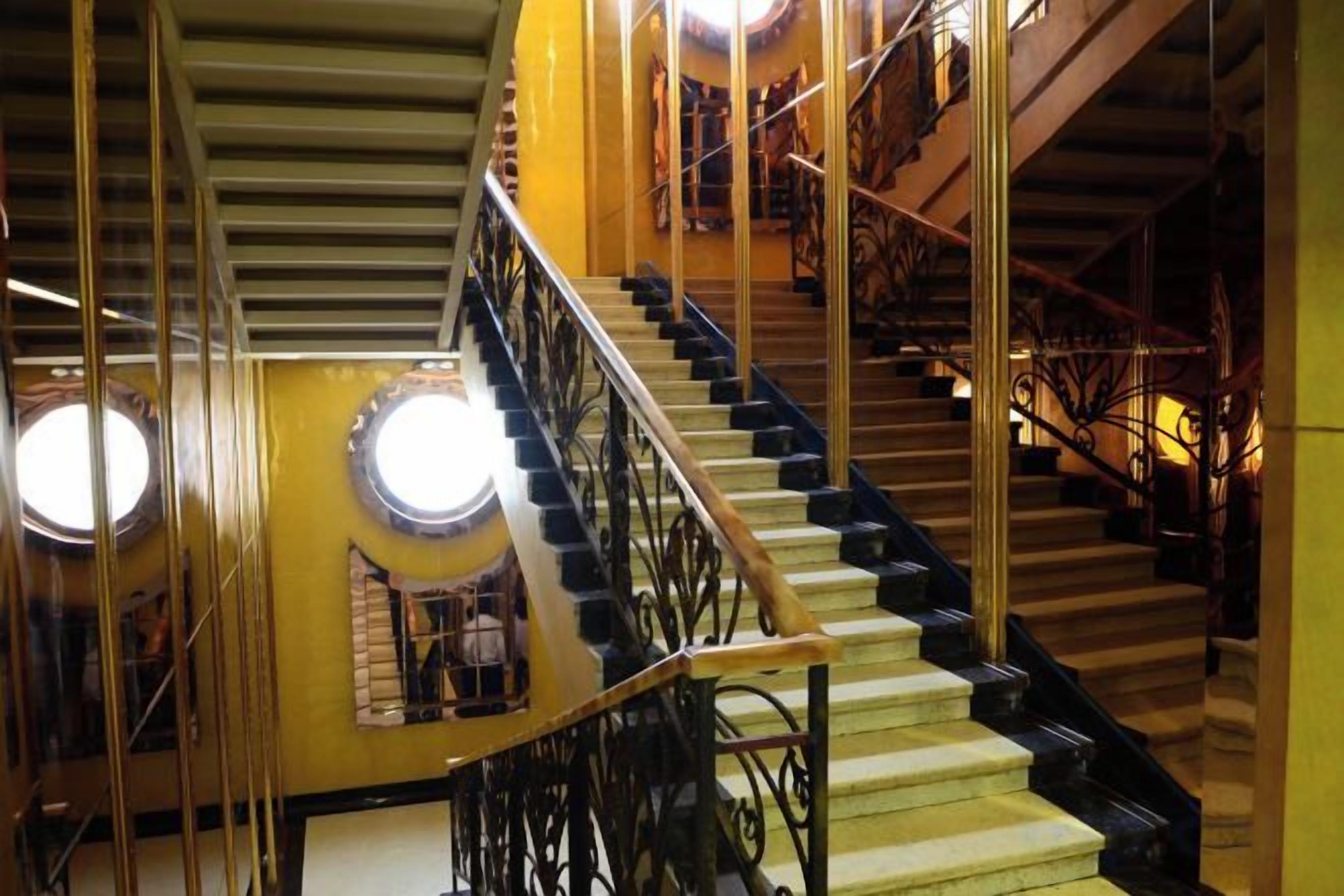 A multi-level interior with a staircase, railings, and circular light fixtures.