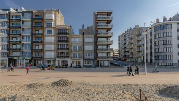 A beachfront building complex with multiple balconies, a sandy beach in the foreground, and a clear sky. - Renovated Ground-floor Apartment in Koksijde (Koksijde)
