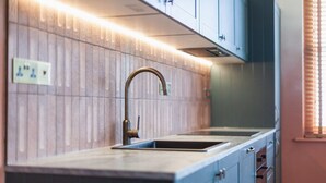 Une cuisine dotée d’un évier à deux bacs, d’un plan de travail en bois et de meubles de rangement bleus.