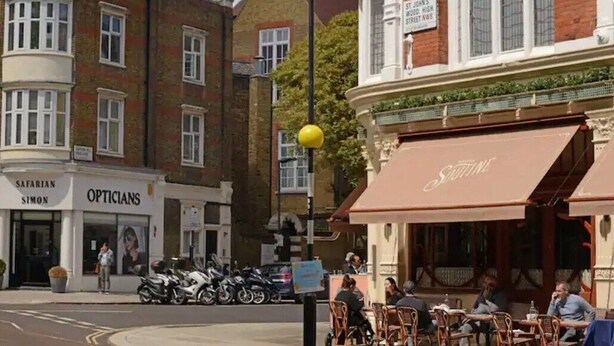 Une vue de rue avec un restaurant appelé « Saffarian » et un bâtiment portant l’enseigne « Opticiens ».
