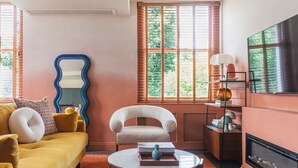 Un salon avec un canapé jaune, un fauteuil blanc, une table basse ronde et une cheminée.