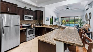 Een moderne keuken met donkerhouten kasten, roestvrijstalen apparatuur en een groot eiland met een granieten aanrecht.