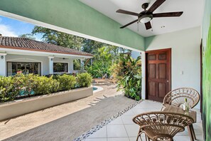 A covered outdoor area with a pool, lounge chairs, and a ceiling fan. - Stylish Home with Chic Decor, Luxury Amenities & Tropical Outdoor Oasis with Sparkling Private Pool (Cabo Velas)