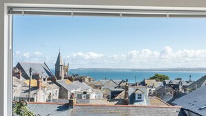 A coastal town with historic buildings and a church, viewed from a window overlooking the sea.