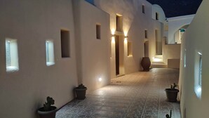 A narrow, tiled corridor with potted plants and illuminated doorways, suggesting a well-lit, possibly upscale lodging area. - Dreamer s Secret Villa II (Santorini)