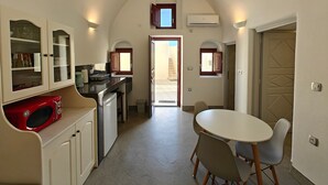 A compact kitchen with a microwave, cabinets, and a dining area with chairs. - Dreamer s Secret Villa II (Santorini)