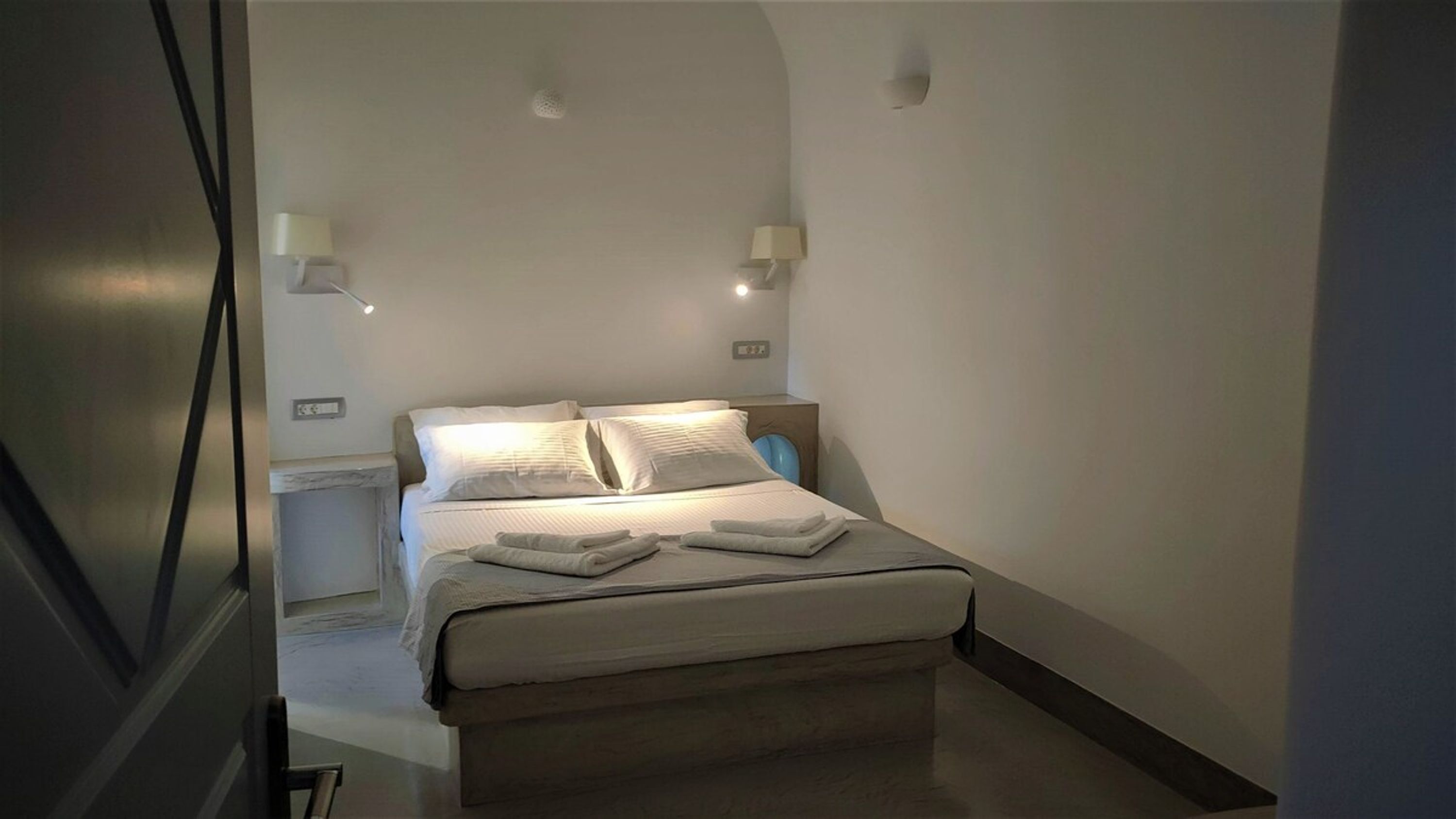 A bedroom with a bed, two bedside lamps, and a nightstand.