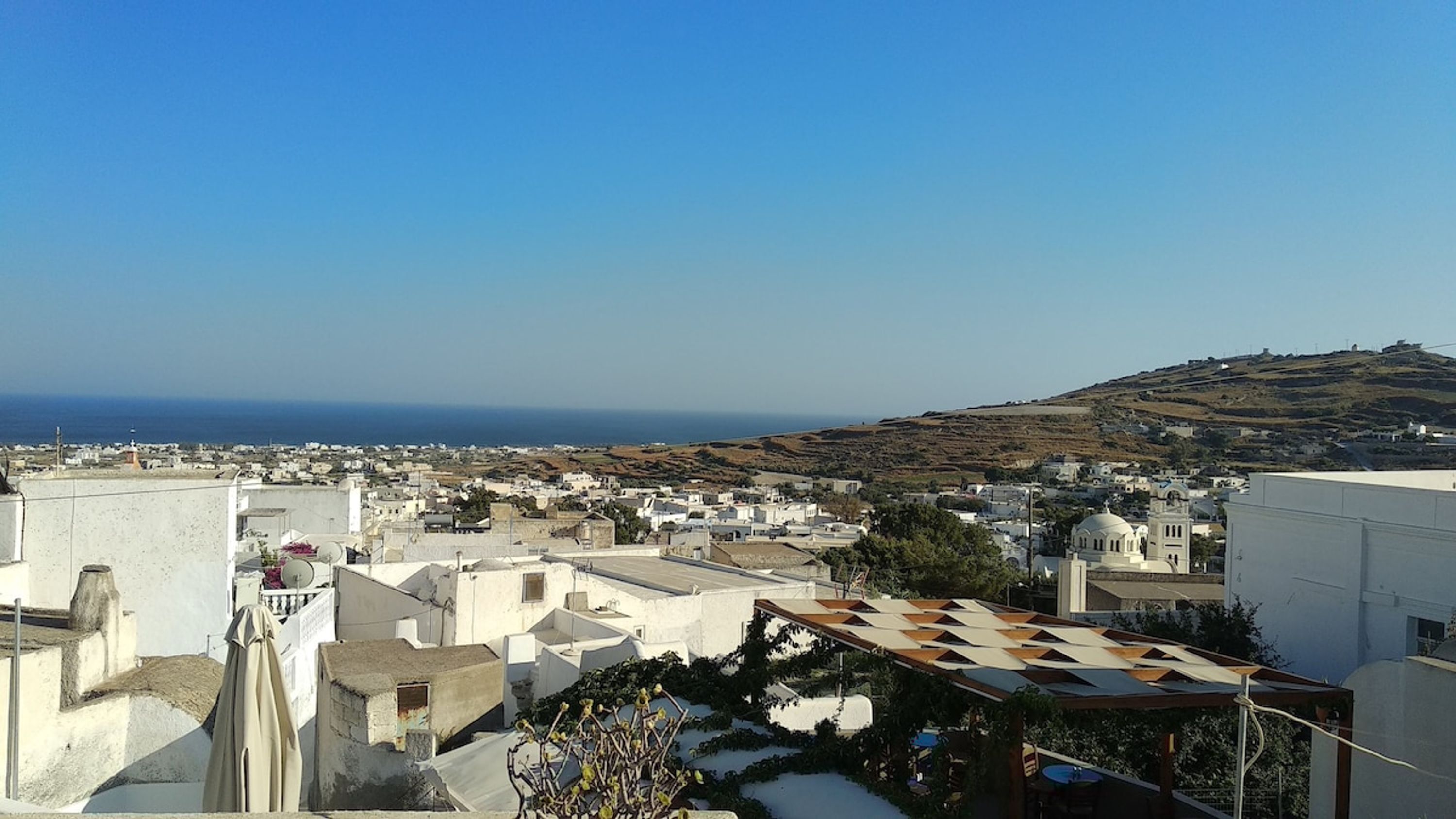 Eine Küstenstadt mit weißen Gebäuden, blauem Himmel und Blick aufs Meer.