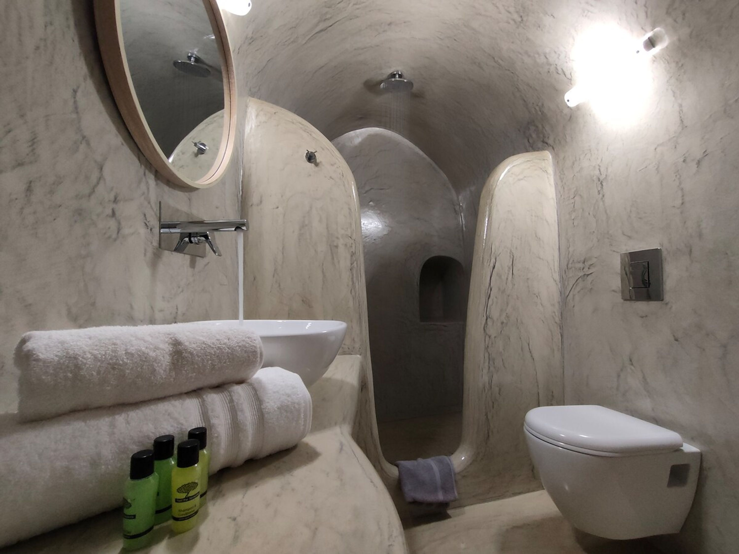 Baño con lavabo, espejo, inodoro y zona de ducha.