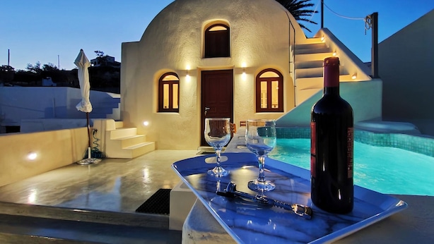 Mesa à beira da piscina com uma garrafa de vinho, copos e saca-rolhas.
