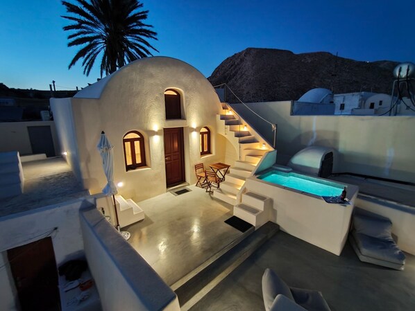 A modern, white-walled building with a pool, a staircase, and a door.