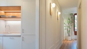 A hallway with white cabinetry, a sink, and a potted plant. - Genteel Home Bib rambla IV (Granada)