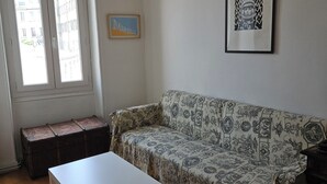A room with a patterned sofa, a white table, a wooden bench, and a framed picture on the wall. - Spacious, bright and central self-contained studio in a chambre d'hôte (Marseille)