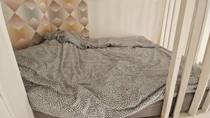 A crib with a patterned blanket, a geometric wall design, and a white crib rail. - Spacious, bright and central self-contained studio in a chambre d'hôte (Marseille)