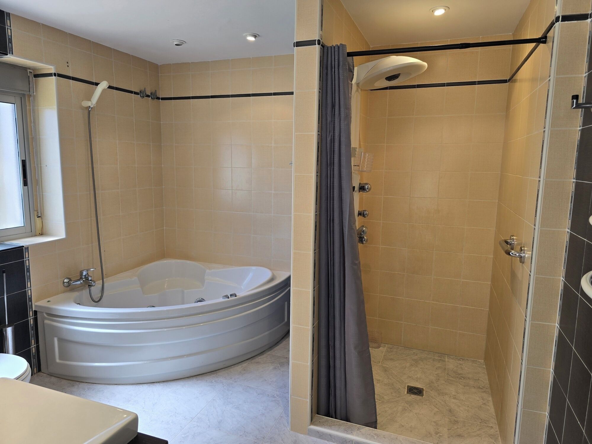 A bathroom with a bathtub, shower, and toilet.
