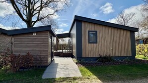 Een modern huis met een houten gevel, een overdekte veranda en een verhard pad dat naar de ingang leidt.