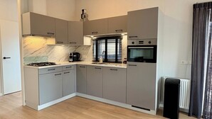 Een kleine keuken met een gasfornuis, koffiezetapparaat en een ingebouwde oven.