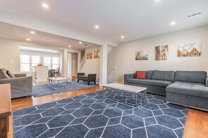 Relax in this stylish living room with a sofa, coffee table, and patterned rug, surrounded by artwork and a staircase leading to an upper level.