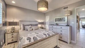 Une chambre à coucher avec un lit en bois, des tables de chevet, une commode et un luminaire suspendu.