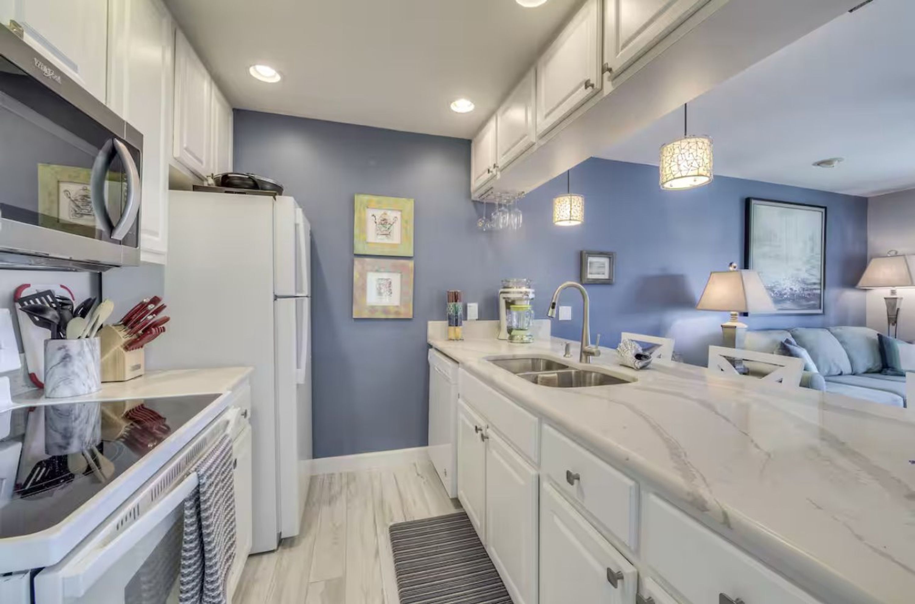 A modern kitchen with white cabinets, a marble countertop, and a built-in oven.