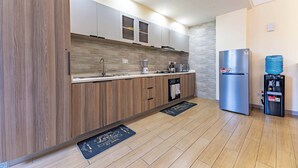 A modern kitchen with wooden cabinets, a stainless steel refrigerator, and a water dispenser.