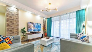 A modern living room with a flat-screen TV, a coffee table, and two sofas.