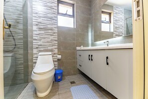 Une salle de bain moderne équipée de toilettes, d’une douche et d’un meuble-lavabo.