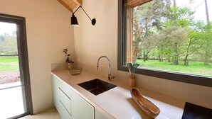 A kitchen with a large window, a sink, and a wooden bowl. - Villa Le Charles with swimming pool ideal for large families and groups (Lit-et-Mixe)