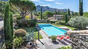 A swimming pool surrounded by lush greenery and stone structures. - La Villa de Robion Su (Robion)