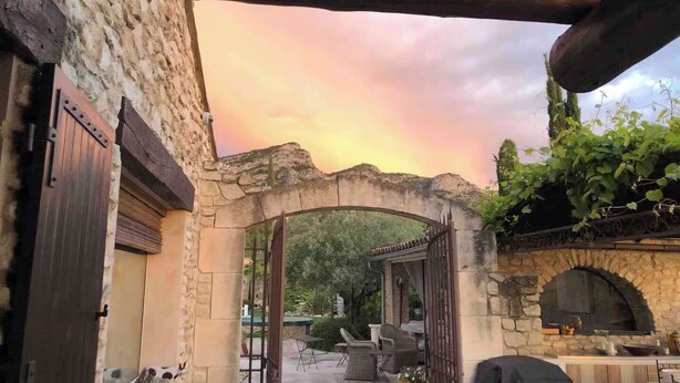 An outdoor patio area with stone walls, a wooden archway, and a view of the sky. - La Villa de Robion Su (Robion)
