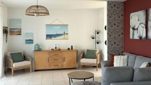 A modern living room with a grey sofa, wooden cabinet, and a hanging light fixture. - House Le Gahignon 2 (Lanton)