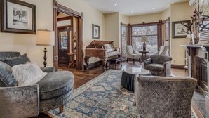 A spacious living room with a grand piano, comfortable seating, and a fireplace. - Victorian Under the Gondola: Main House (Steamboat Springs)