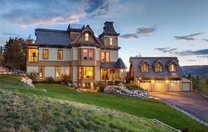 Une grande maison à deux étages, dotée d’un porche avant imposant, de nombreuses fenêtres et d’un garage.