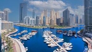 Un puerto deportivo con numerosas embarcaciones amarradas, rodeado de edificios altos y un cielo despejado.