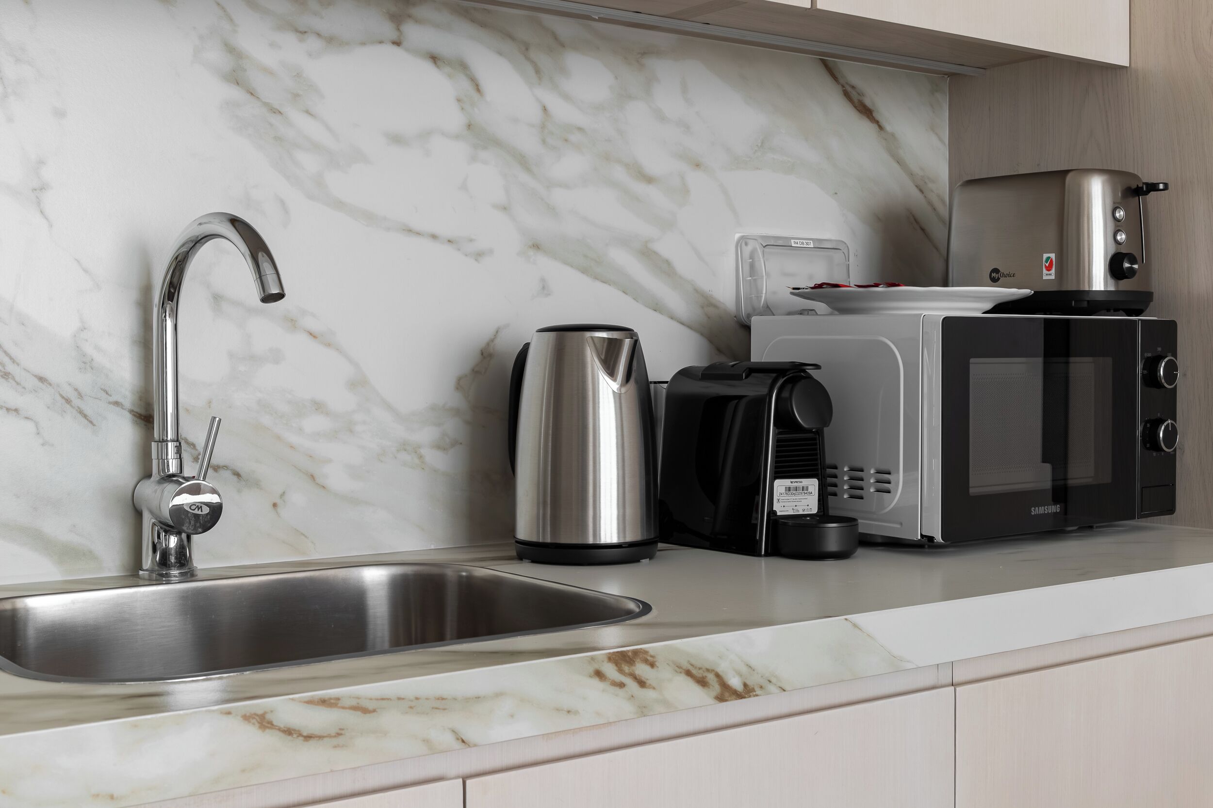 A modern kitchen with a stainless steel sink, a coffee maker, and a microwave.