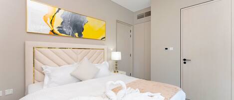 A hotel room with a large bed, a headboard, a painting, a wardrobe, and a door.