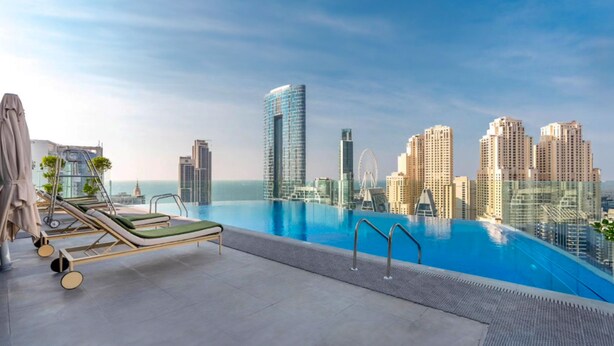 Piscina infinita en la azotea con sillones, con vistas a un horizonte urbano con rascacielos.