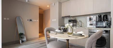 Une cuisine moderne avec un coin repas, comprenant une table ronde, des chaises et un grand miroir.