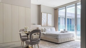 Un dormitorio moderno con una cama grande, una mesa de comedor con sillas y vistas a la ciudad a través de amplios ventanales.