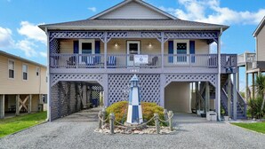 A two-story building with a balcony, a sign reading "Waves and Wings," and a number "1887" on the facade. - Waterfront Stay w/ Stunning Views, Beach Access, Outdoor Shower & Lift (North Topsail Beach)