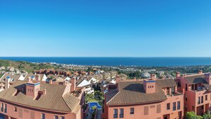 A coastal town with terracotta-roofed buildings, a clear blue sky, and a view of the sea. - ELZE Panoramic Sea View Luxury Apartment (Calahonda)