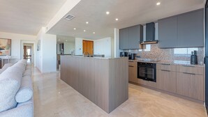 A modern kitchen with a central island, built-in appliances, and a sleek design. - ELZE Panoramic Sea View Luxury Apartment (Calahonda)