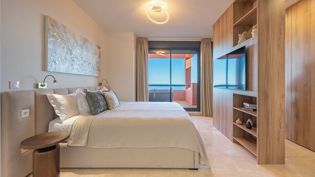 A modern bedroom with a large bed, a wooden wardrobe, a TV, and a view of the outside. - ELZE Panoramic Sea View Luxury Apartment (Calahonda)