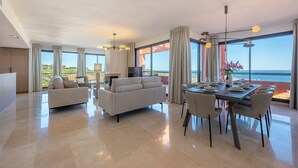 A spacious living area with a large dining table, sofas, and a view of the ocean. - ELZE Panoramic Sea View Luxury Apartment (Calahonda)