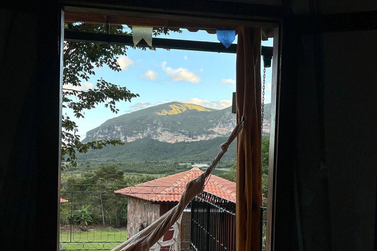 A room with a view of a mountain, a hammock, and a balcony.